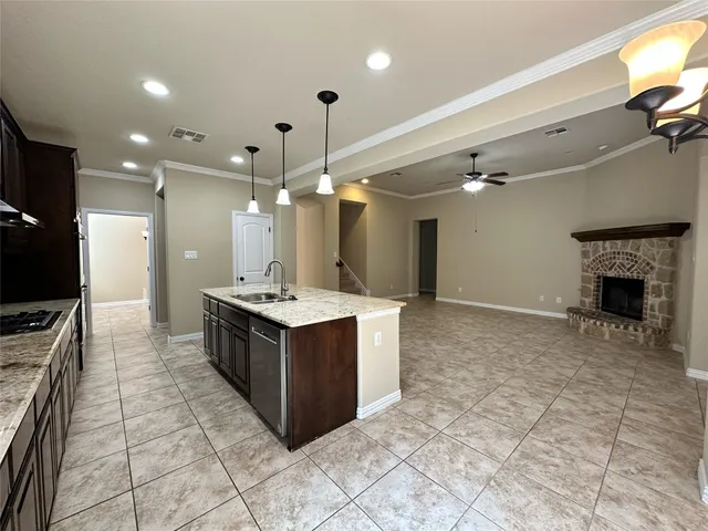 a large kitchen with a stove a sink dishwasher a refrigerator and a fireplace with wooden floor