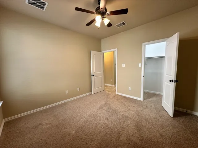 an empty room with closet and a chandelier fan