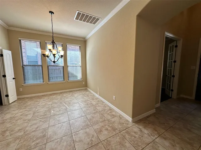 a view of an empty room with window and chandelier