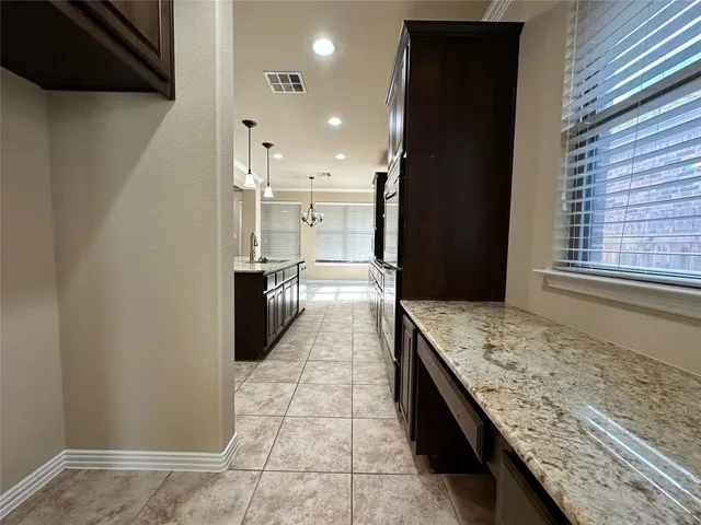 a large kitchen with granite countertop a stove a sink and a refrigerator