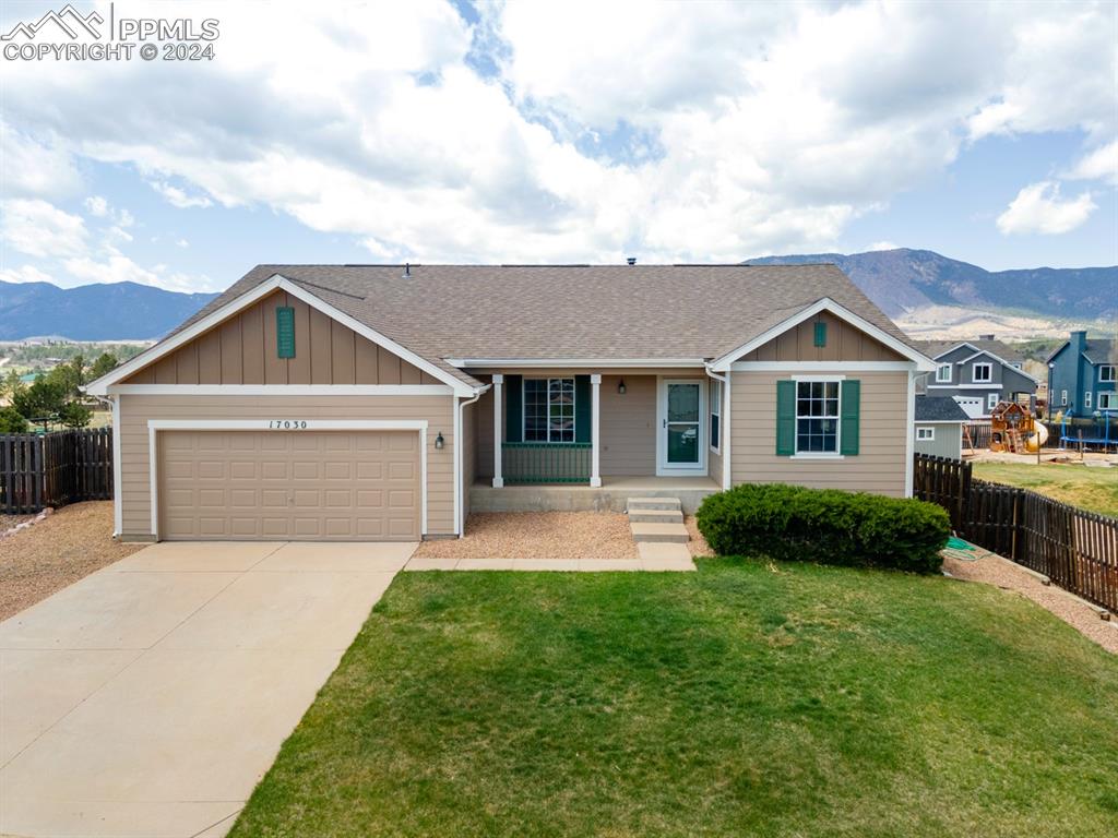 Single story home featuring a mountain view, a garage, and a front lawn