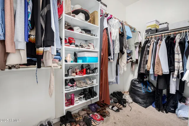 a view of walk in closet with clothes and shoes