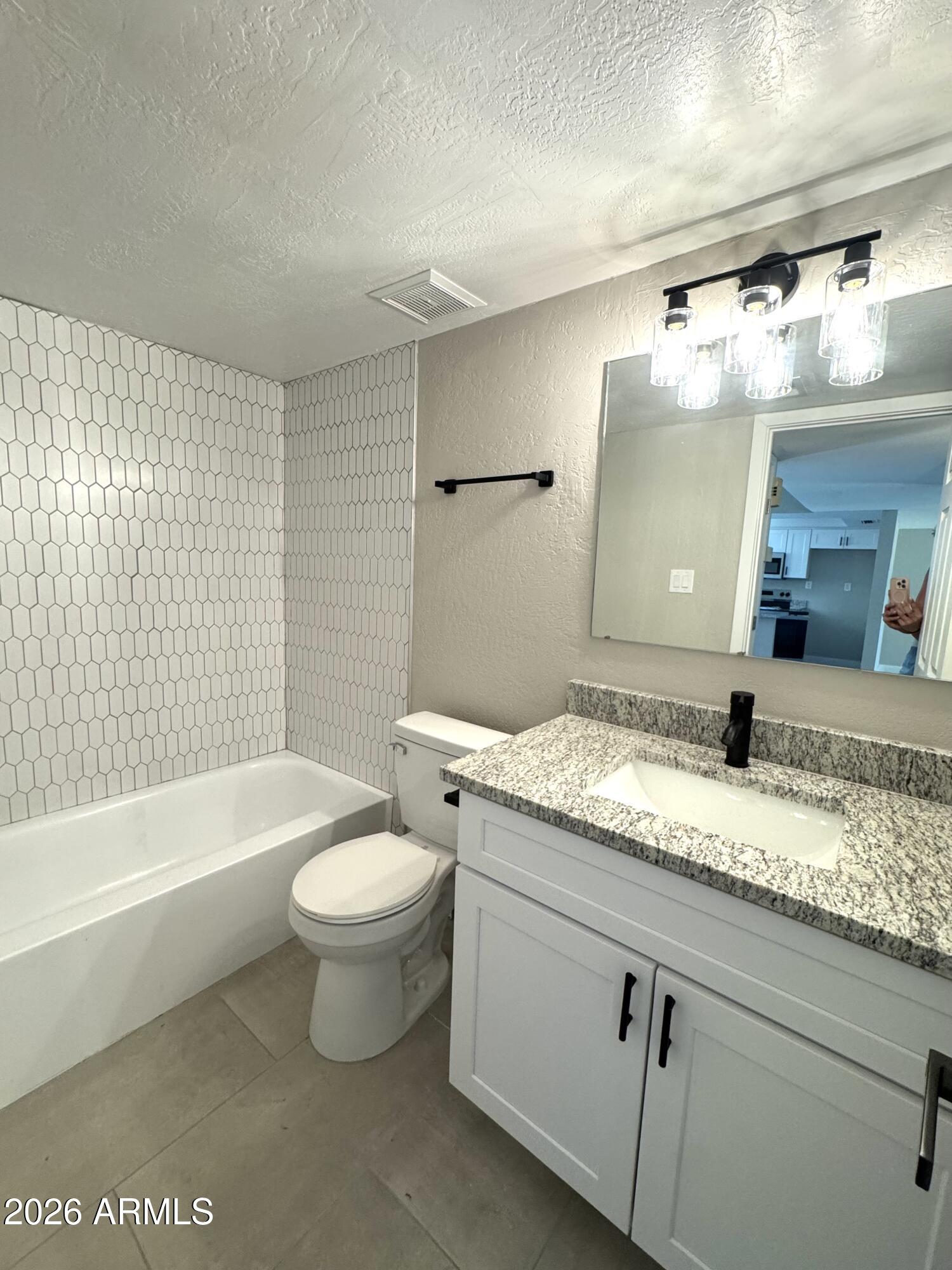 2003 North 51st Way Phoenix, AZ 85008 - Photo 11 of 22 a bathroom with a granite countertop sink a toilet a mirror and bathtub