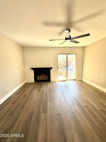 a view of an empty room with wooden floor fireplace and a window