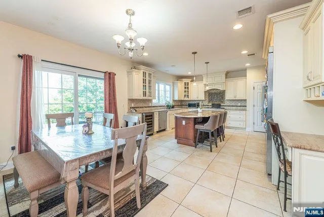 a kitchen with stainless steel appliances granite countertop a stove top oven a sink dishwasher a dining table and chairs with wooden floor