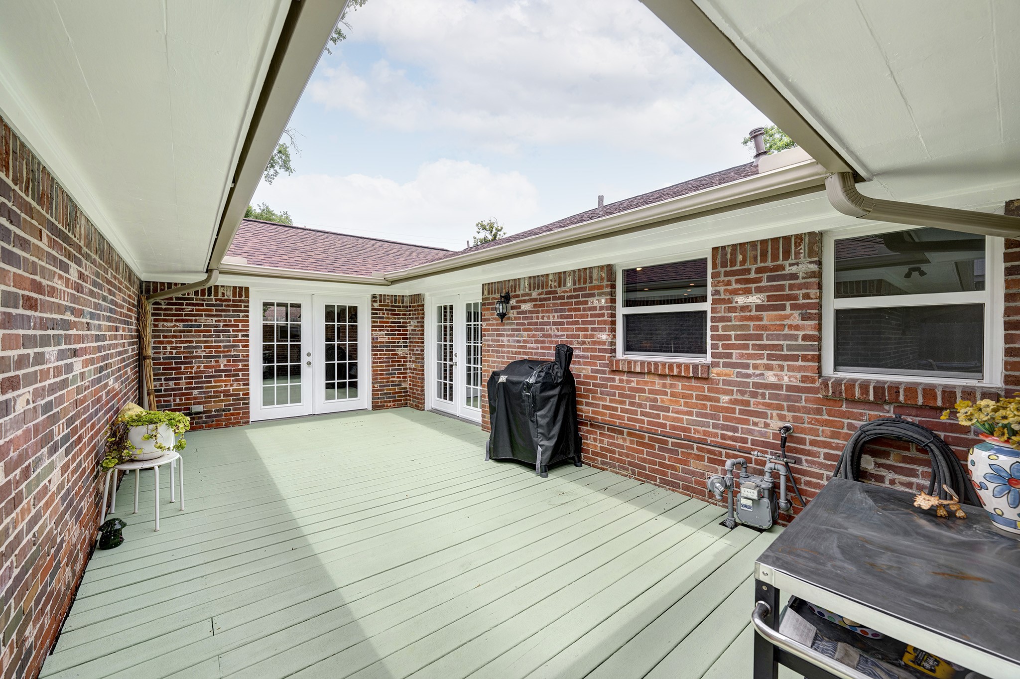 1111 Clovis Road Houston, TX 77008 - Photo 23 of 32 The sage green deck contrasts nicely against the earth-toned brick backdrop and seamlessly blends indoor and outdoor living.