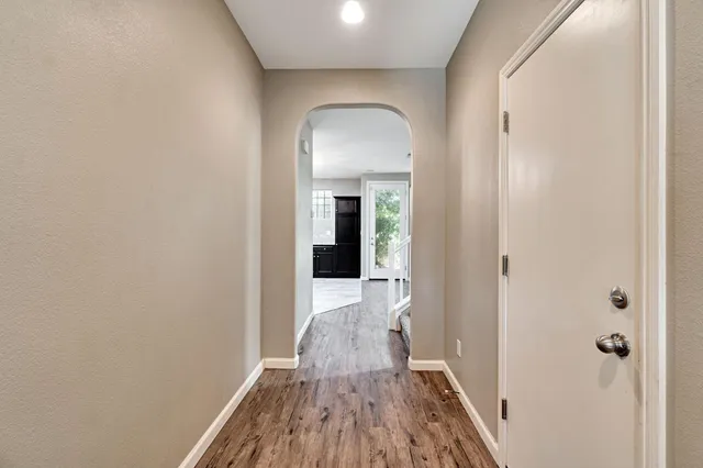 a view of a hallway with wooden floor and a bathroom
