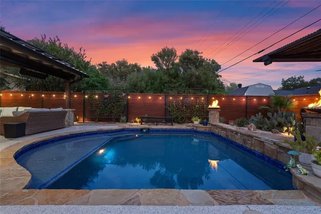 a view of swimming pool with seating space and trees in the background