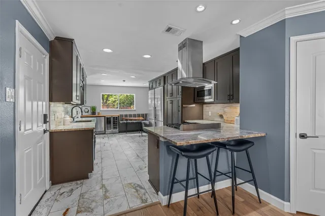 a kitchen with stainless steel appliances kitchen island granite countertop a table chairs sink and cabinets