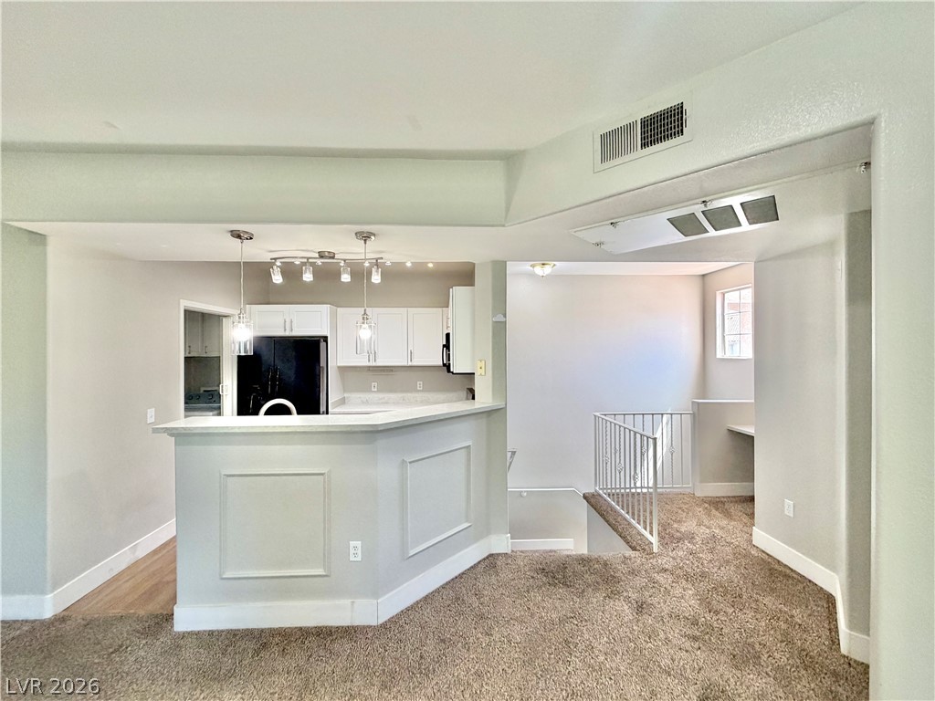 8555 West Russell Road, Unit 2018 Las Vegas, NV 89113 - Photo 9 of 23 An open-concept living area with a functional kitchen island seamlessly transitions into plush carpeted space, with a window nook and stairwell.