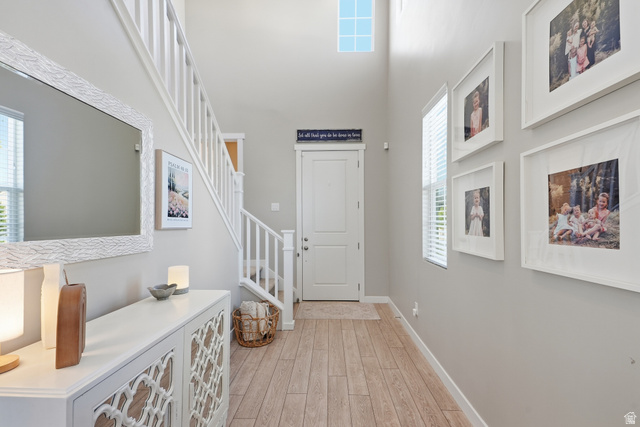 3244 West 1670th Street North Provo, UT 84601 - Photo 5 of 56 Two-story entry foyer featuring wood-finish flooring, a contemporary white console with geometric door detailing, and a prominent staircase with white railings