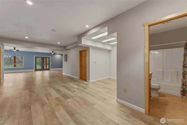 a view of a livingroom with wooden floor and a bathroom