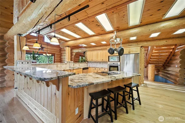 a kitchen with stainless steel appliances kitchen island granite countertop a table chairs sink and cabinets