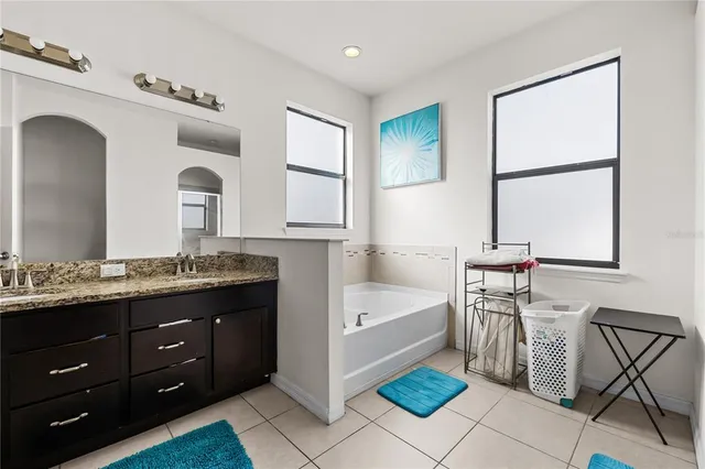 a spacious bathroom with a granite countertop sink a mirror and a bathtub