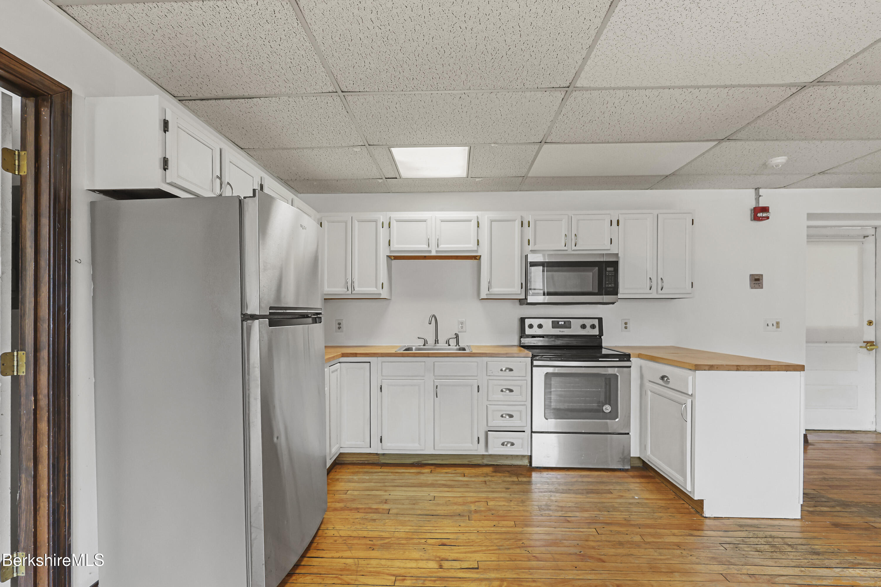 55 Crystal Street, Unit 8 Lenox, MA 01242 - Photo 7 of 12 a kitchen with stainless steel appliances a refrigerator sink and white cabinets