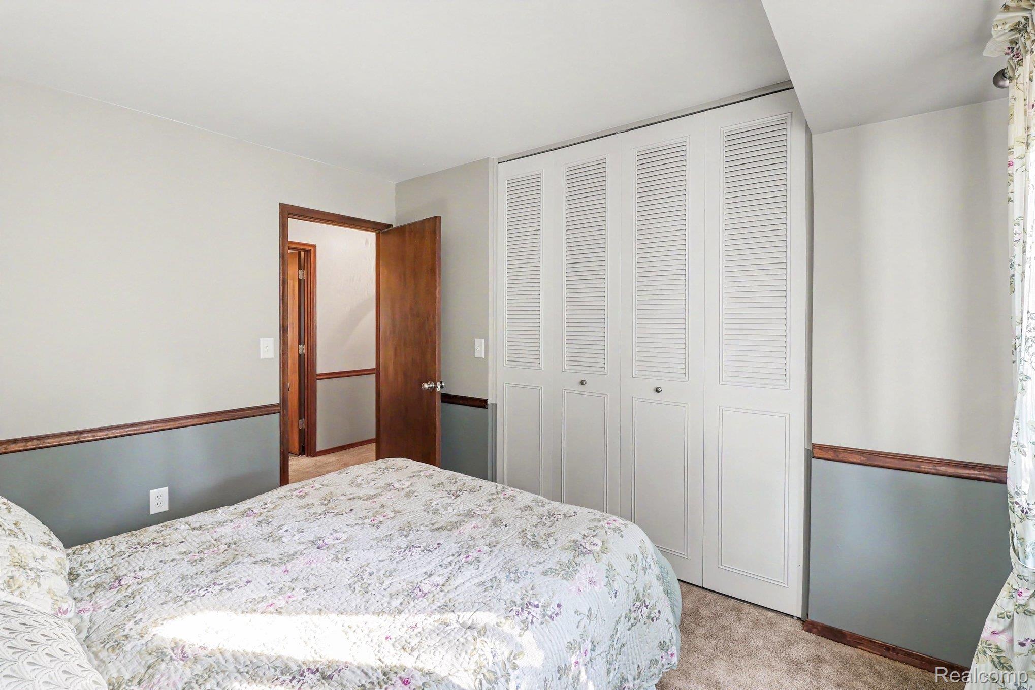 6300 North Raddatz Road Fowlerville, MI 48836 - Photo 26 of 42 White louvered bifold closet doors, wood trim, and a warm neutral carpet