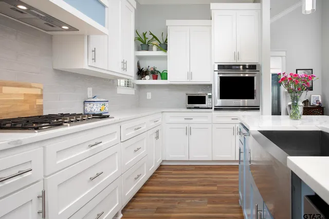 a kitchen with granite countertop a sink stainless steel appliances and white cabinets