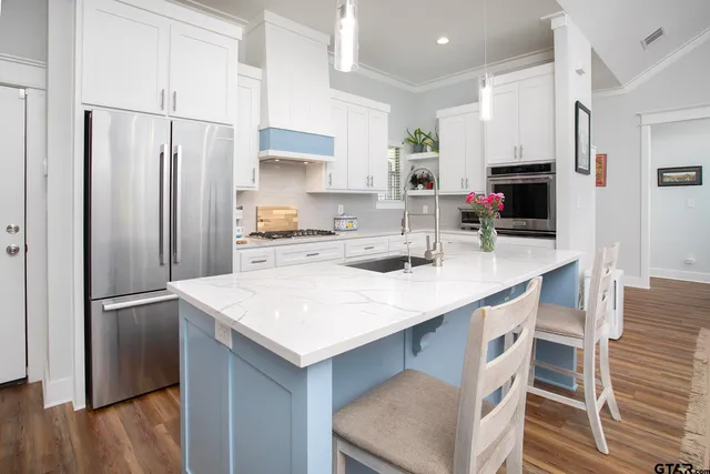 a kitchen with stainless steel appliances a sink a stove a refrigerator and cabinets