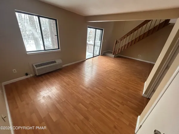 a view of an empty room with wooden floor and a window