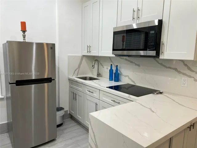 a kitchen with a refrigerator a sink dishwasher a dining table and chairs with wooden floor