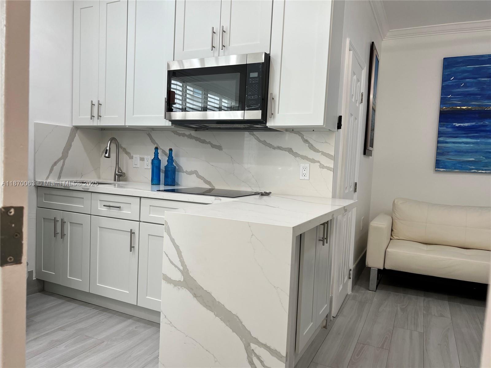 3710 Collins Avenue, Unit N103 Miami Beach, FL 33140 - Photo 35 of 53 a kitchen with white cabinets and a sink