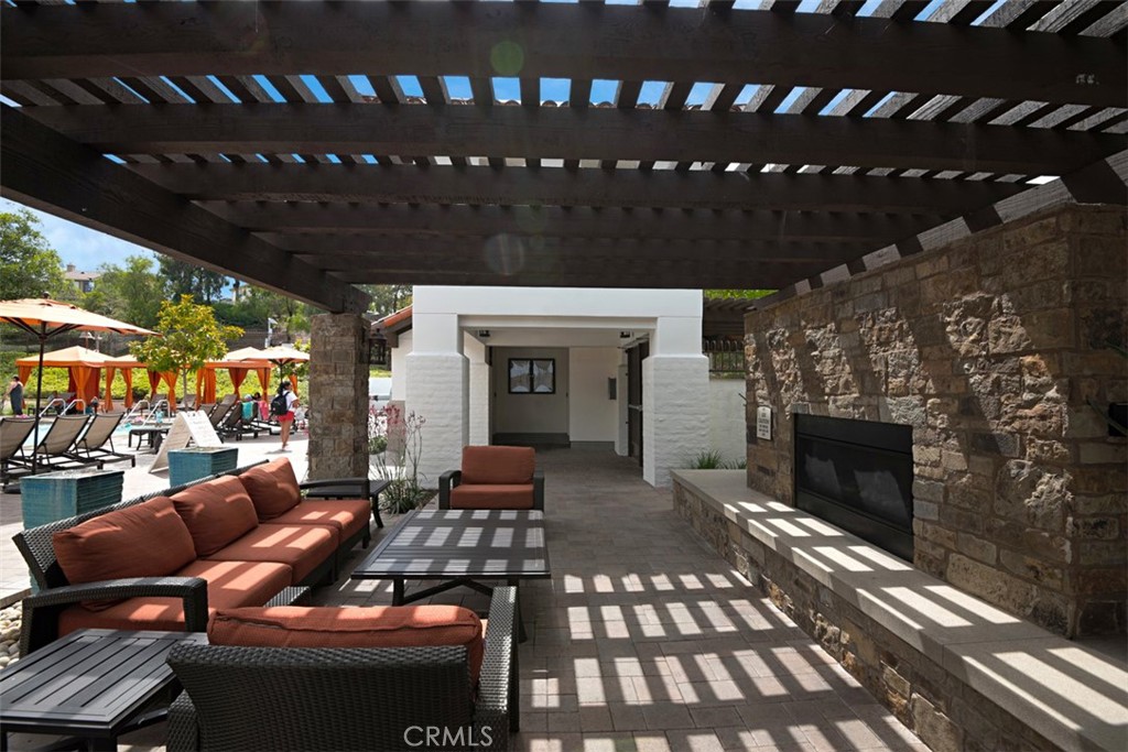 56 Acorn Ridge Rancho Santa Margarita, CA 92688 - Photo 53 of 57 Community Lounge Area: Covered outdoor seating area with a stone fireplace, paver flooring, and pergola-style shade creates a comfortable gathering space near the pool.