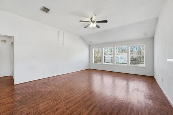 a view of an empty room with wooden floor and a window