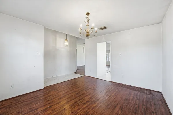 a view of an empty room with wooden floor and a ceiling fan