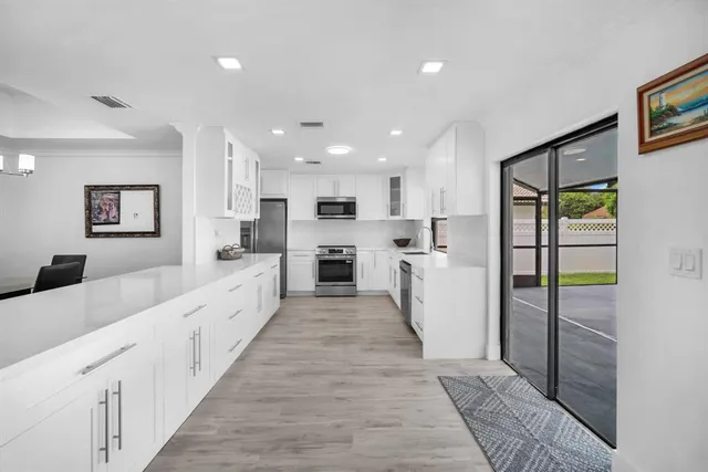 a large white kitchen with kitchen island a sink a stove and refrigerator