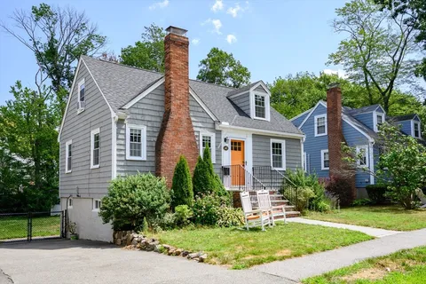 a front view of a house with a yard and potted plants