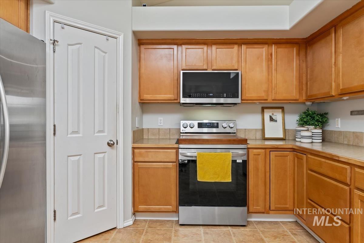 80 Cobblestone Court Middleton, ID 83644 - Photo 7 of 48 Kitchen featuring light wood cabinetry, a stainless steel range, a stainless steel microwave, and tile flooring