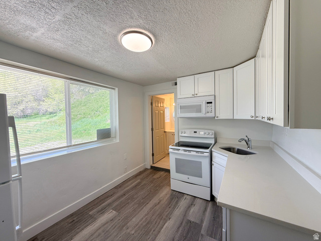 548 27th Street Ogden, UT 84403 - Photo 4 of 13 Kitchen with white appliances, white cabinets, dark wood-type flooring, a textured ceiling, and light stone counters