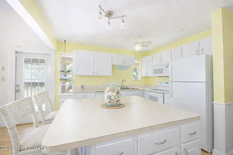 a kitchen with a refrigerator a stove a sink and white cabinets with wooden floor
