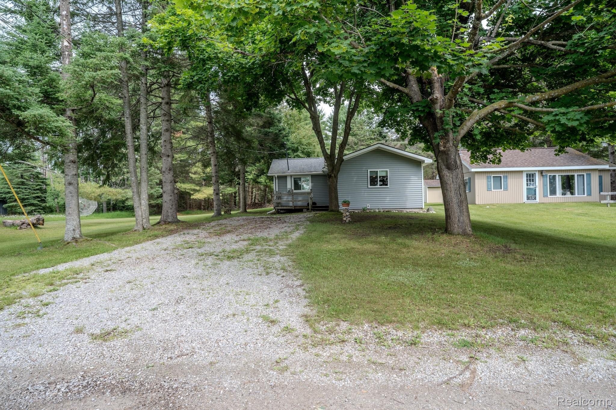 4350 Shrew Road Lincoln, MI 48742 - Photo 32 of 32 Gravel driveway leading to two distinct structures, surrounded by mature trees and a manicured lawn