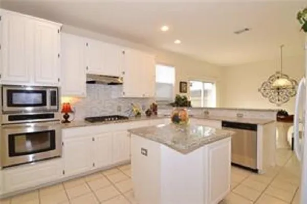 a kitchen with granite countertop a sink stove and cabinets