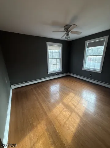 an empty room with windows and ceiling fan