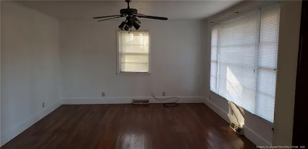 an empty room with wooden floor and windows