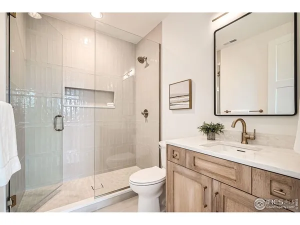 a bathroom with a toilet a sink a glass door a shower and a mirror