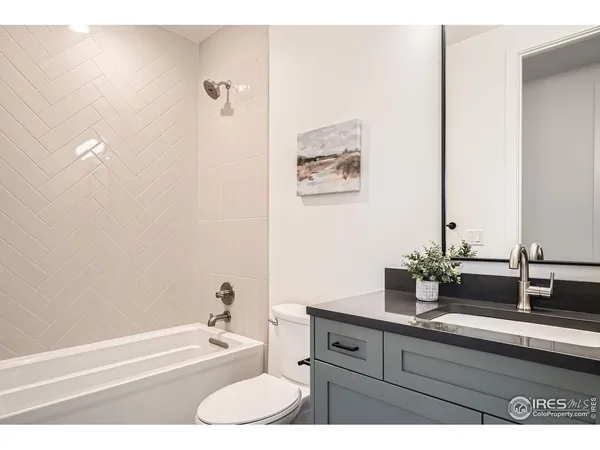 a bathroom with a granite countertop sink a toilet a mirror and bathtub