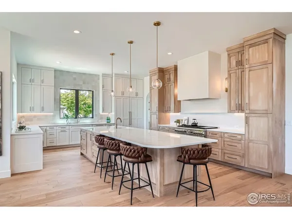 a kitchen with stainless steel appliances granite countertop a stove a sink a refrigerator a dining table and chairs with wooden floor