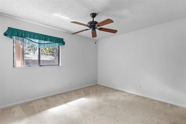 an empty room with a chandelier fan and windows