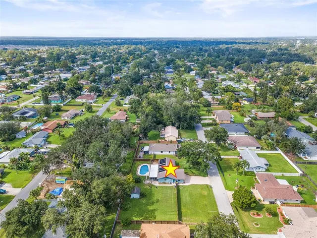 an aerial view of residential houses with outdoor space and trees