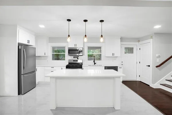 a kitchen with stainless steel appliances kitchen island a refrigerator sink and cabinets