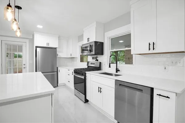 a kitchen with a sink a stove a refrigerator and white cabinets