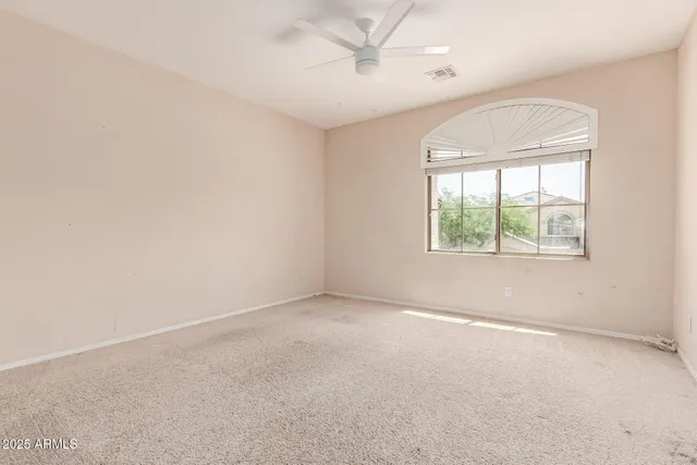 an empty room with a window and a ceiling fan
