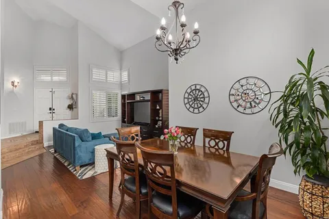 a living room with furniture and a dining table with wooden floor