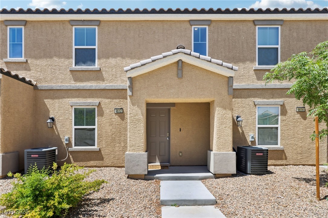 View of front of property featuring stucco siding and cooling unit