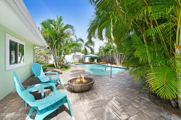 a view of swimming pool with lawn chairs and plants