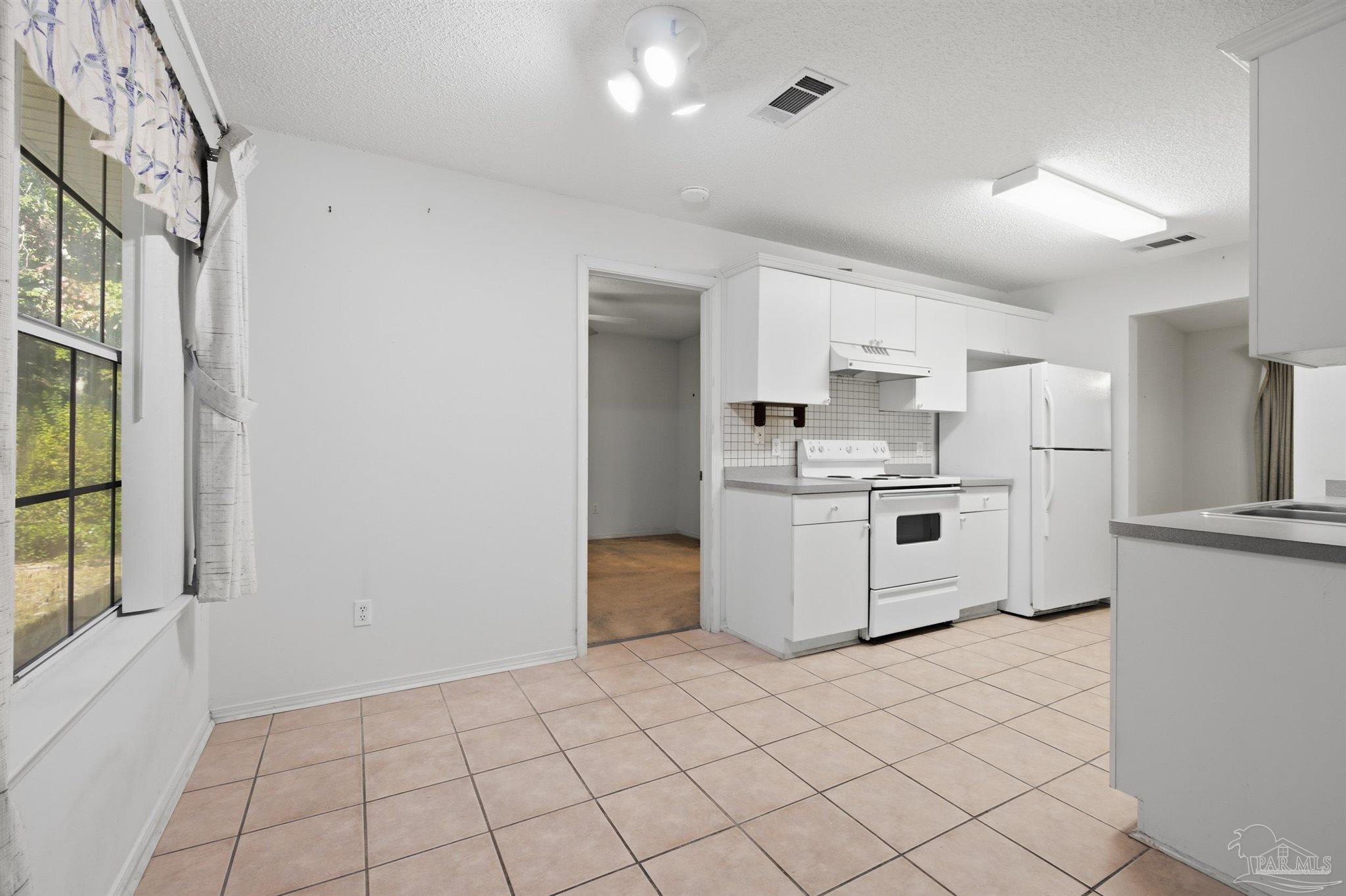 4327 Chantilly Way Milton, FL 32583 - Photo 5 of 32 a kitchen with white cabinets and white appliances