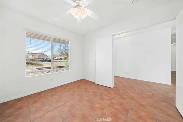a view of an empty room with window and chandelier fan
